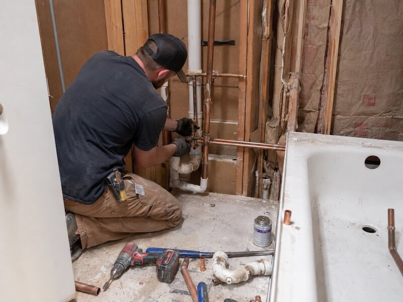 Plombier modifiant les canalisations d’une salle de bain