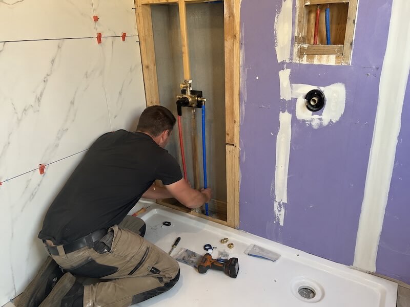 Plombier installant les raccordements d’une baignoire